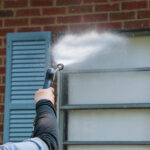 man pressure washing window