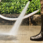 person washing driveway with soft washing machine